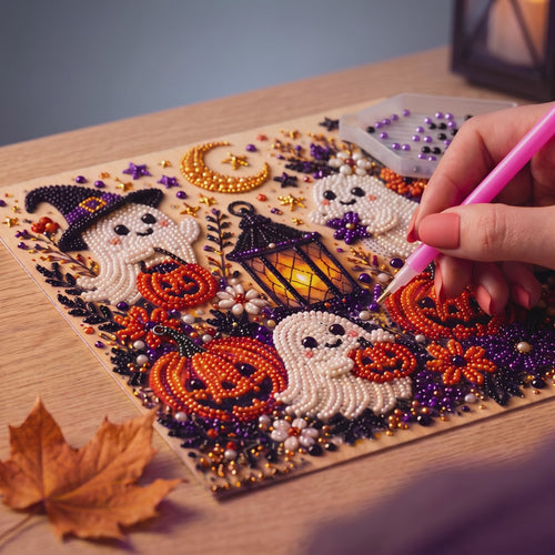 Manos colocando gemas de resina sobre un lienzo de Halloween.
